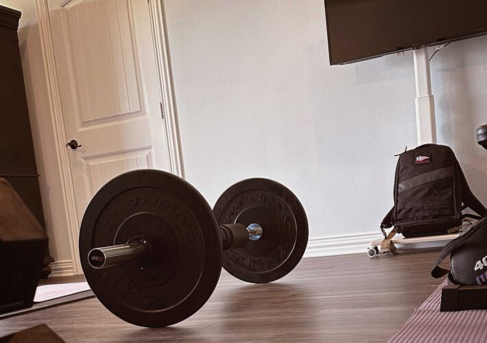 home gym setup with dumbbells, barbell, bench, and yoga mat
